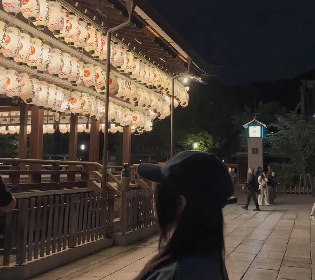 夜晚神社挂满灯笼的舞殿，下方露出 Chishan 的头顶